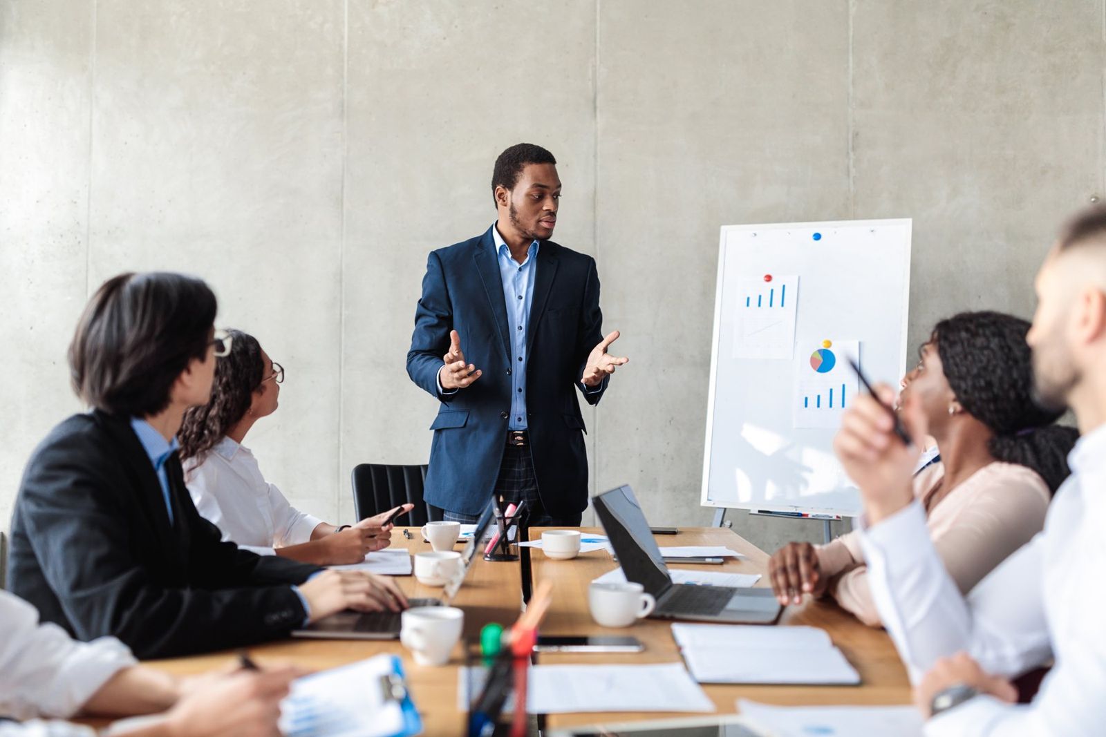 A presenter leading a team meeting in front of a flip chart