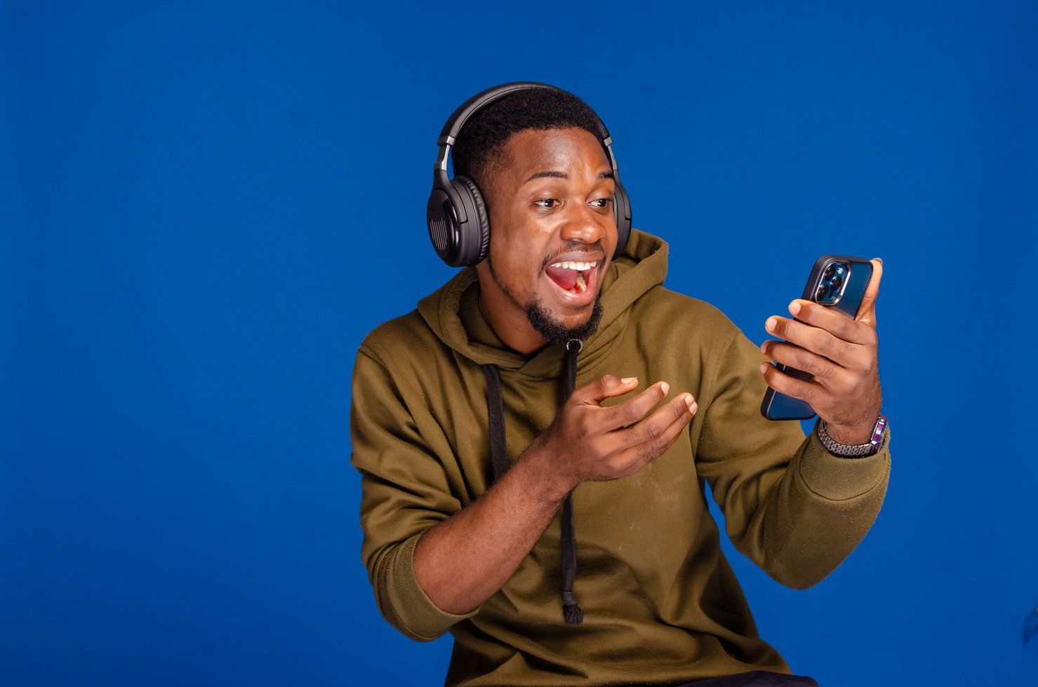 A young man with headphones reacting excitedly to his phone