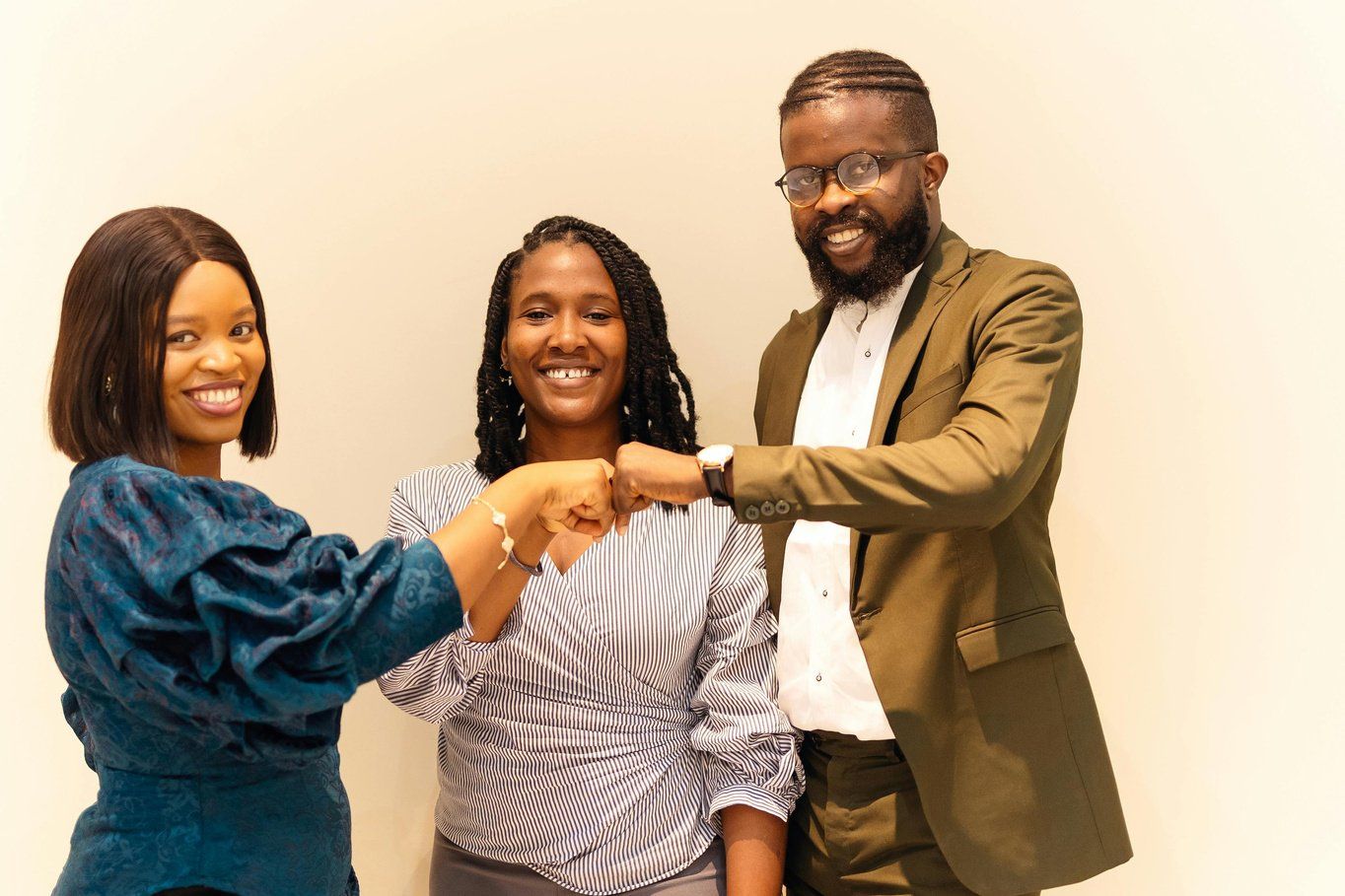Three colleagues bumping fists and smiling